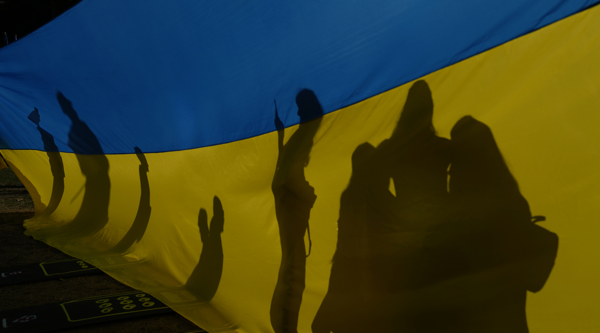 Μια οικογένεια ποζάρει για μια φωτογραφία μπροστά από μια μεγάλη ουκρανική σημαία κατά τη διάρκεια της Ημέρας Ανεξαρτησίας της Ουκρανίας